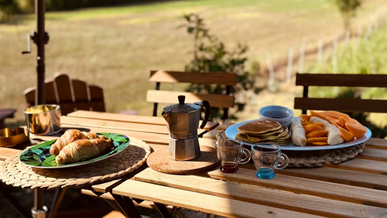 Colazione su un tavolo all'aperto: croissant, moka, pancake e frutta