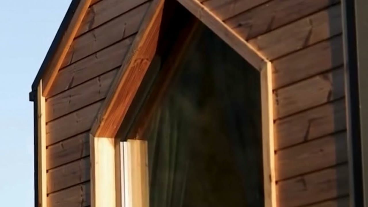 Facciata in legno con finestra a punta, illuminata dal sole basso